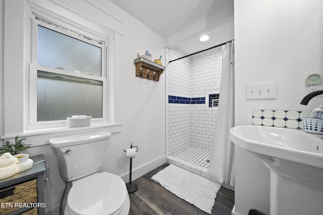 full bathroom featuring a shower stall, toilet, wood finished floors, and a sink