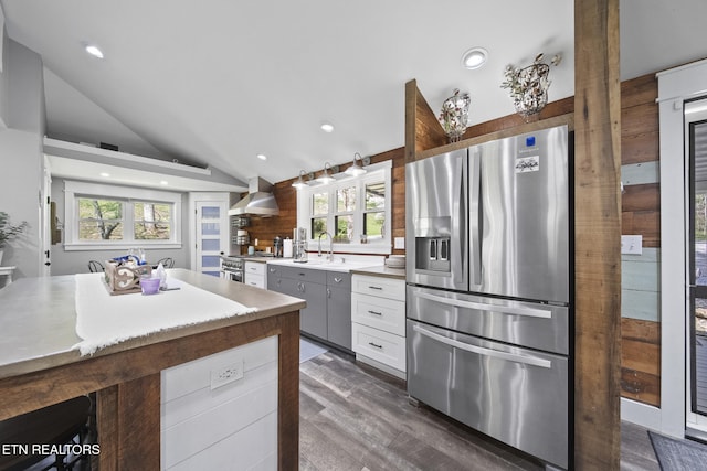kitchen featuring recessed lighting, lofted ceiling, dark wood-style floors, stainless steel appliances, and wall chimney range hood