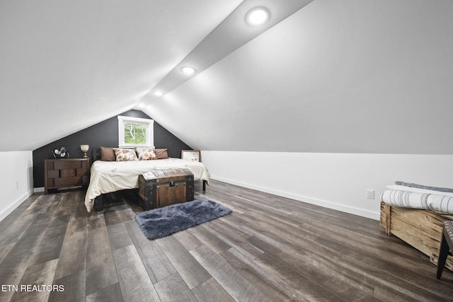 bedroom with vaulted ceiling, wood finished floors, and baseboards
