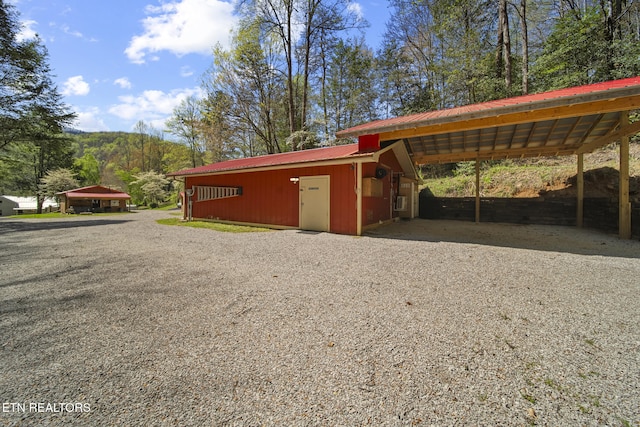 view of outdoor structure with driveway and a carport