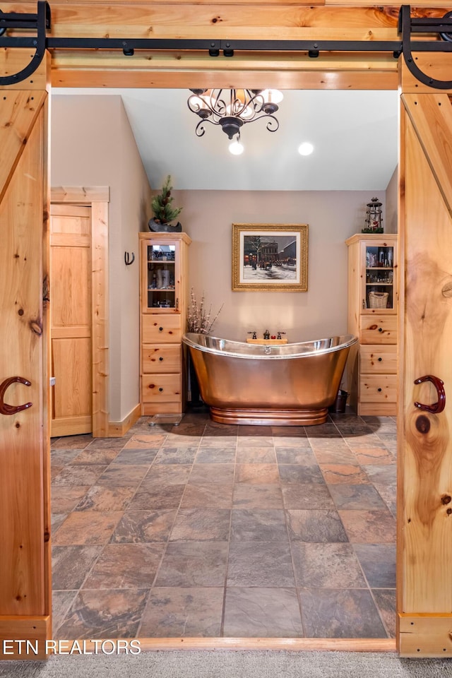 bathroom with stone finish flooring, a freestanding bath, and baseboards