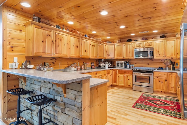 kitchen with appliances with stainless steel finishes, light wood-style floors, a peninsula, and recessed lighting