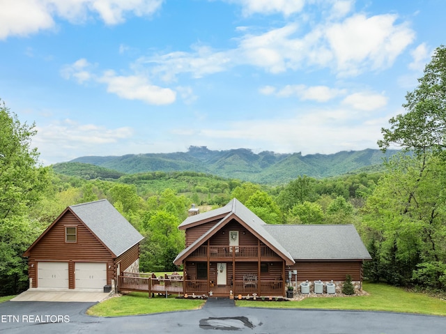 view of front of home with an outdoor structure, a wooded view, a chimney, a detached garage, and a deck with mountain view