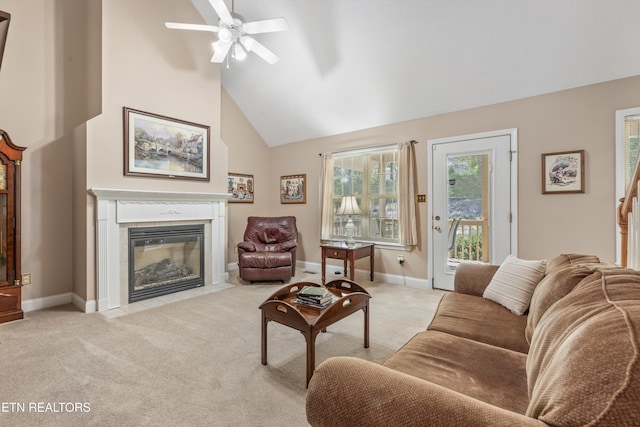 living room featuring vaulted ceiling, baseboards, light colored carpet, ceiling fan, and a tile fireplace