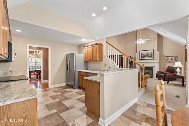 kitchen with a peninsula, vaulted ceiling, recessed lighting, light stone countertops, and appliances with stainless steel finishes