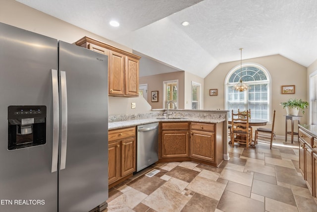 kitchen featuring a sink, an inviting chandelier, stainless steel appliances, a peninsula, and lofted ceiling
