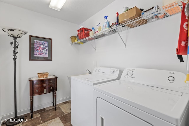laundry room with baseboards, stone finish floor, washer and dryer, and laundry area