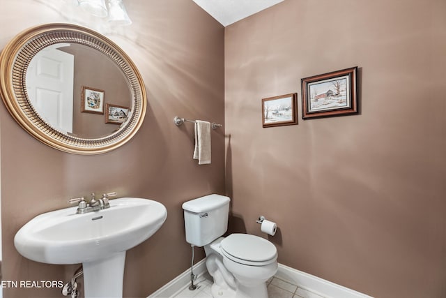 bathroom with tile patterned flooring, toilet, baseboards, and a sink
