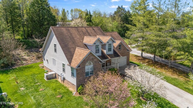 exterior space with an attached garage, aphalt driveway, roof with shingles, and a front yard