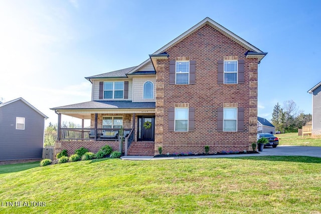 view of front of home with brick siding, a front lawn, and covered porch