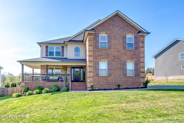 view of front of house featuring a front lawn, brick siding, fence, and covered porch