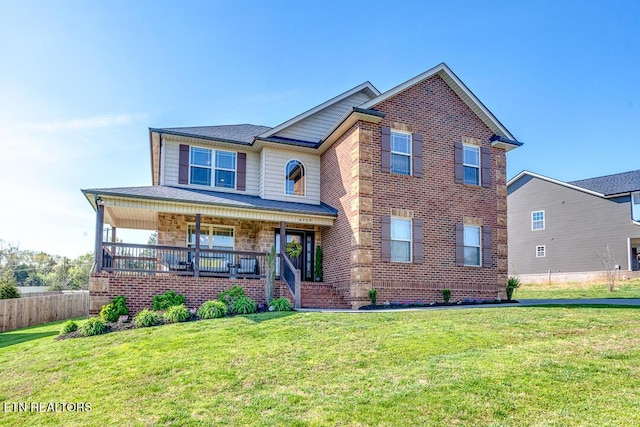 traditional home with fence, covered porch, a front lawn, and brick siding