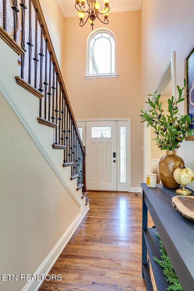 entryway featuring wood finished floors, a wealth of natural light, and ornamental molding