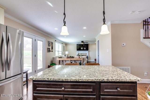 kitchen featuring freestanding refrigerator, visible vents, dark brown cabinets, and ornamental molding