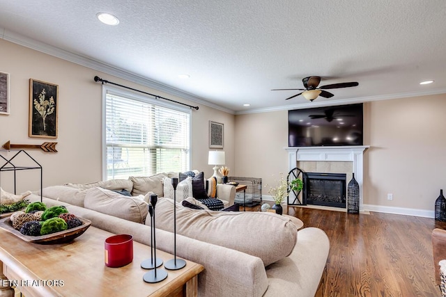 living room with recessed lighting, ceiling fan, ornamental molding, a fireplace, and dark wood-style flooring