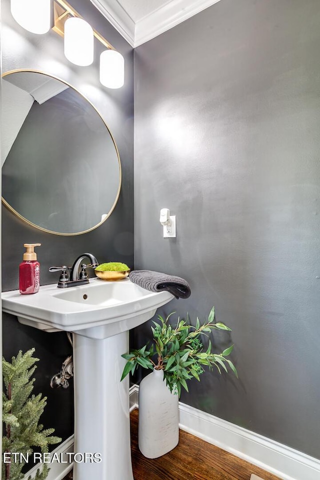 bathroom with baseboards, ornamental molding, and wood finished floors