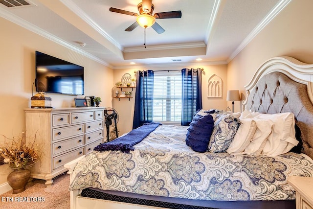 bedroom with a ceiling fan, crown molding, a raised ceiling, light colored carpet, and visible vents