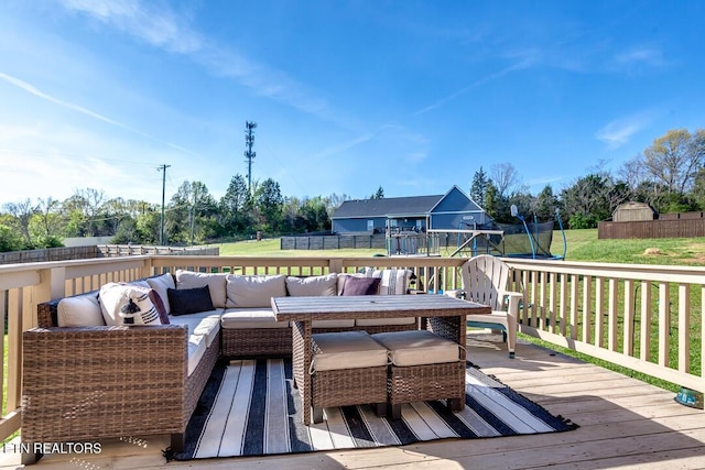 wooden terrace featuring outdoor lounge area, a trampoline, a lawn, and fence