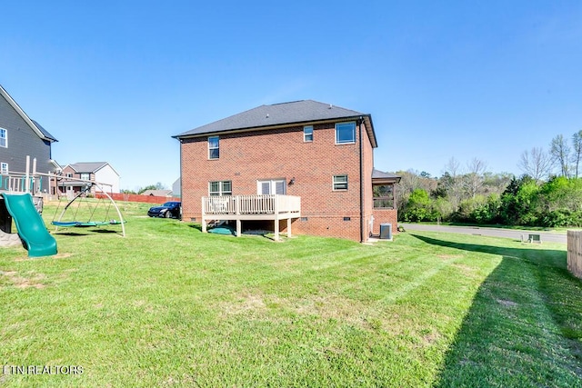rear view of property with brick siding, a yard, central air condition unit, and a playground