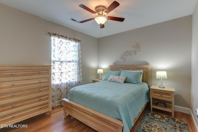 bedroom featuring visible vents, baseboards, wood finished floors, and ceiling fan