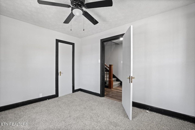 unfurnished bedroom with a textured ceiling, carpet flooring, baseboards, and ceiling fan