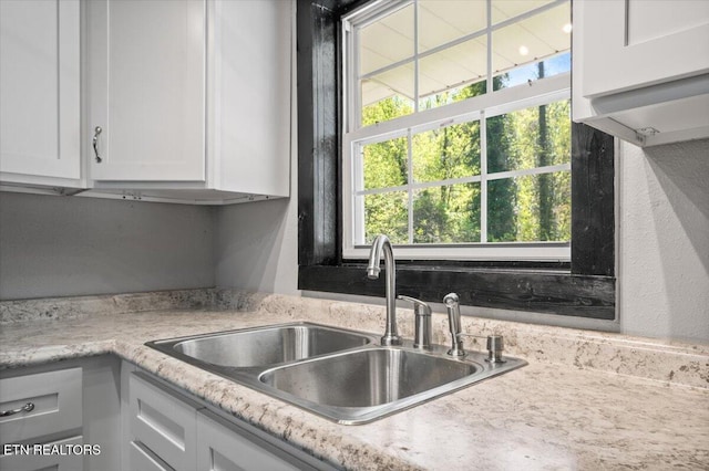 interior details with white cabinets, light countertops, and a sink