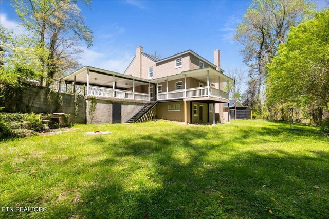 rear view of house with a wooden deck, a lawn, a chimney, and stairs
