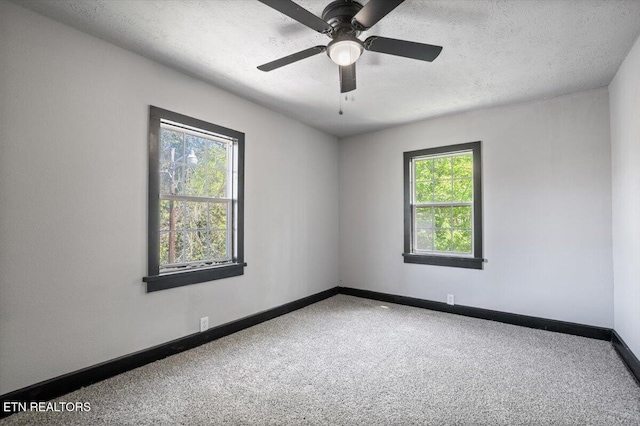 carpeted spare room featuring baseboards, a textured ceiling, and ceiling fan