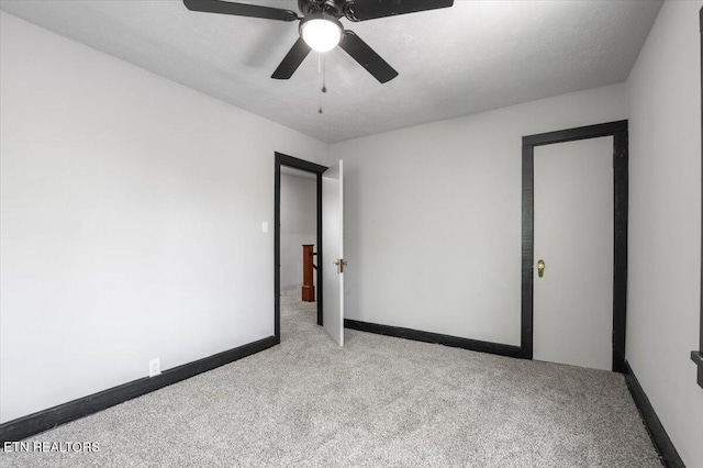 carpeted spare room featuring baseboards and ceiling fan