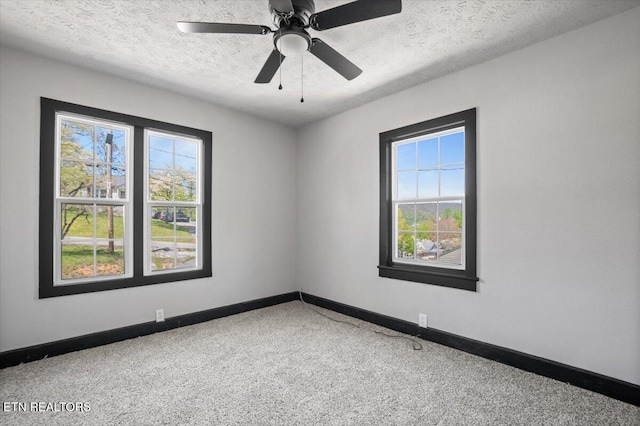 empty room with carpet floors, a ceiling fan, a textured ceiling, and baseboards