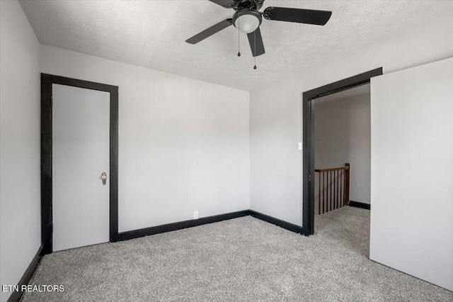 unfurnished room with carpet, a textured ceiling, baseboards, and ceiling fan