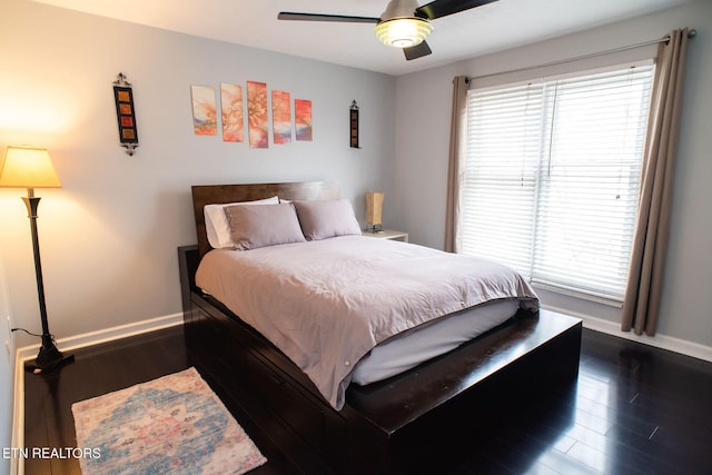 bedroom with baseboards, multiple windows, a ceiling fan, and dark wood-style floors