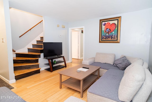 living room with stairway, baseboards, and light wood-style floors