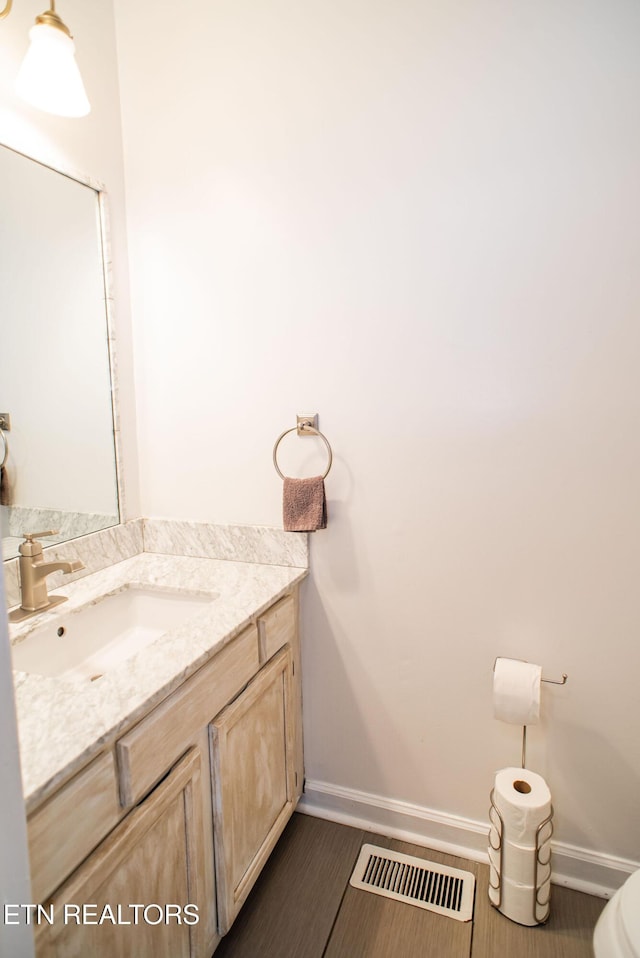 half bathroom with toilet, visible vents, baseboards, and vanity