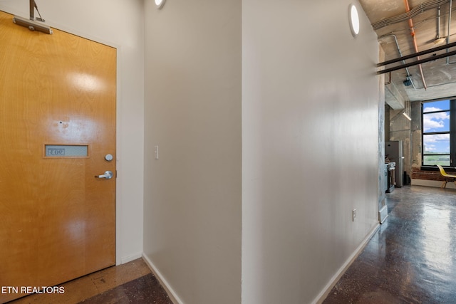corridor with concrete flooring and baseboards