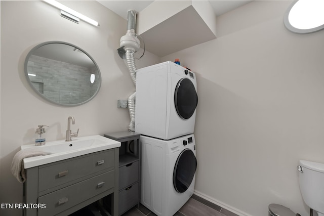 washroom featuring baseboards, stacked washer / dryer, and laundry area