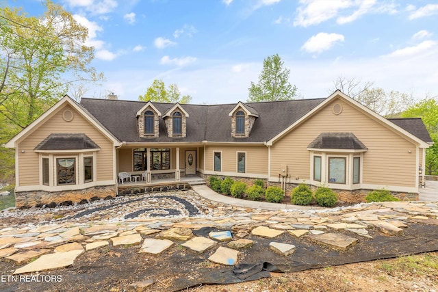 rear view of property featuring a porch, a shingled roof, and stone siding