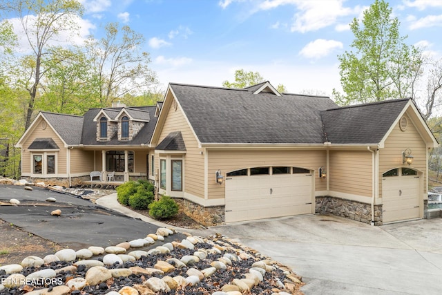 cape cod-style house featuring stone siding, concrete driveway, and a garage