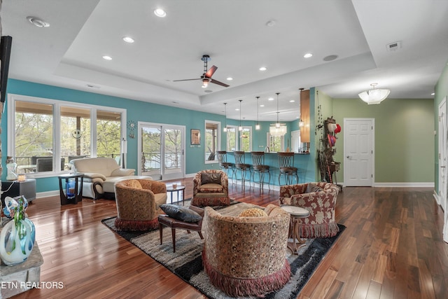 living area featuring baseboards, wood finished floors, a tray ceiling, and recessed lighting