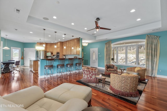 living room featuring a tray ceiling, recessed lighting, and ceiling fan