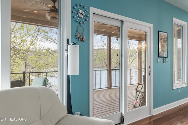 doorway with wood finished floors, baseboards, and ceiling fan