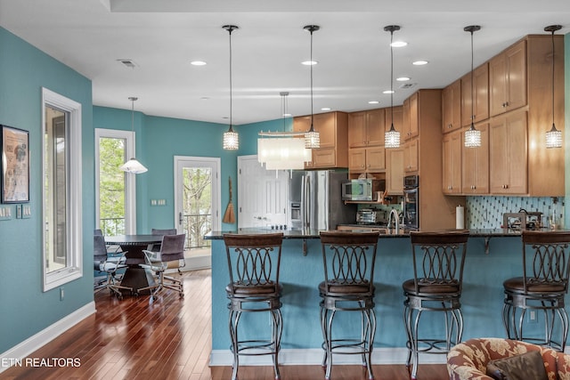 kitchen with dark countertops, stainless steel appliances, visible vents, a peninsula, and dark wood-style floors