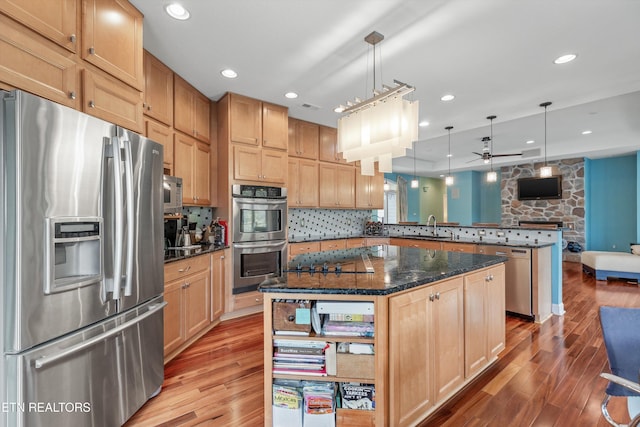 kitchen featuring a sink, open floor plan, ceiling fan, stainless steel appliances, and a peninsula