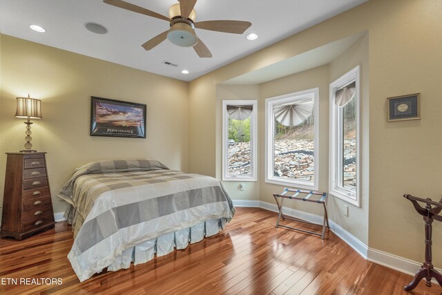 bedroom with wood finished floors, visible vents, and multiple windows