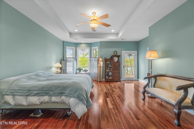 bedroom featuring baseboards, recessed lighting, wood finished floors, access to outside, and a raised ceiling