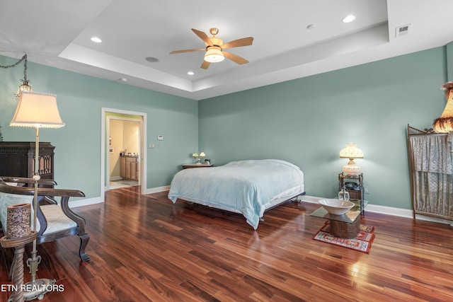 bedroom featuring wood finished floors, a raised ceiling, baseboards, visible vents, and recessed lighting