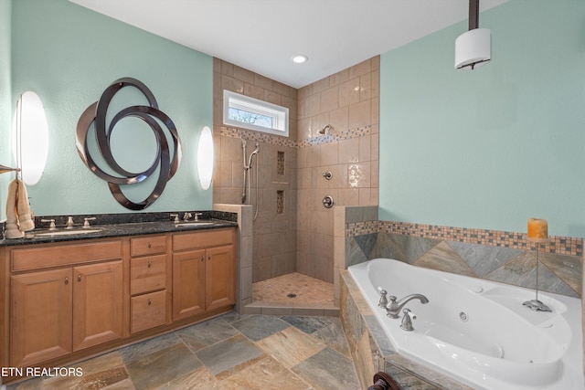 bathroom featuring a tile shower, a tub with jets, a sink, and double vanity
