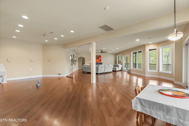 living area with arched walkways, wood finished floors, visible vents, and recessed lighting