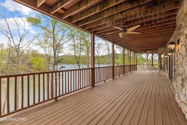 deck with ceiling fan and a water view