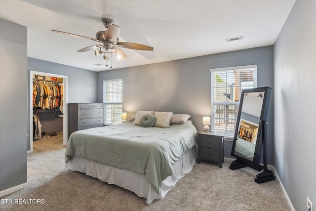 bedroom with a closet, baseboards, light carpet, and a spacious closet